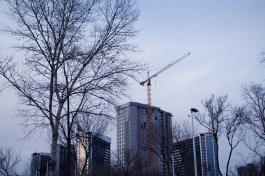 Kiev, Ukrayna. 2 Ocak 2021. Mor gökyüzüne karşı tamamlanmamış çok katlı bina ve inşaat vincinin silueti. Moda tonu çok iyi. İnşaat işi, yatırım, emlak konsepti.