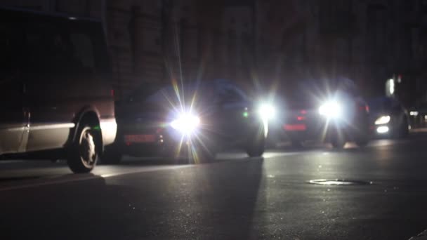乌克兰基辅。2021年10月1日。傍晚时分，开着前灯的汽车沿着一条路缓缓行驶。汽车正停在红绿灯处的塞车处.大城市的大街小巷尖峰时刻. — 图库视频影像