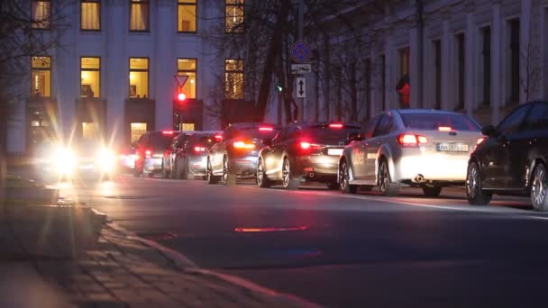 乌克兰基辅。2021年10月1日。晚上，开着前灯的汽车沿着柏油路行驶。汽车正停在红绿灯处的塞车处.大城市的大街小巷尖峰时刻. — 图库视频影像