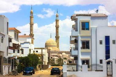 Kahire, Mısır. 1 Mayıs 2021. Çağdaş Mısır mimarisi. Apartman binaları olan şehir caddesi, binalar arasındaki toprak yol. Mavi gökyüzüne karşı uzun kuleler. Afrika çölünde bir kasaba. Sıcak bir ülke.