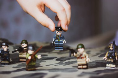 Kyiv, Ukrayna. 9 Mart 2022. Çocuğun elindeki memurun heykeli. Bir çocuk İkinci Dünya Savaşı 'nın LEGO askerlerini oynuyor. Kamuflaj üniformalı oyuncak askerler, makineli tüfek. Silahlı kuvvetlerin savaş askeri oluşumları