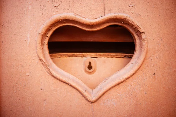 Postal mail slot in terracotta red weathered door. Mailbox letter box in a shape of a big heart with a key hole in a lock. Valentine\'s Day Mailbox for love letters. Feeling in love abstract background