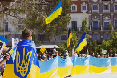 Madrid, İspanya. 8 Mayıs 2022. Rusya ile savaşta Ukrayna 'yı desteklemek için toplanın. Sarı mavi Ukrayna bayraklı bir kalabalık. Mızrakla bayrağa sarılmış bir adam. Rusya işgaline karşı protestocular.