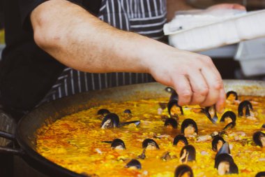 Profesyonel bir şef büyük bir kazanda midyeli geleneksel bir İspanyol yemeği olan paella hazırlar. Deniz mahsullü klasik İspanyol paella 'sı. Sokak Yemekleri Festivali. Sokakta sağlıklı yemek pişirmek..