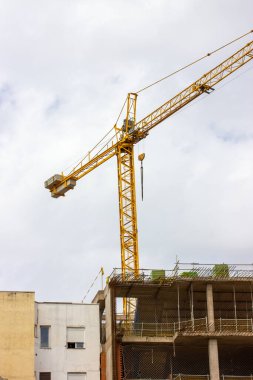 Şehirde inşa edilen çok katlı bir panelin ön cephesi. İskele, arka planda inşaat vinci. İnşaat işi. Emlak konut kavramına yatırım.