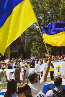 Madrid, İspanya. 7 Mayıs 2022. Ukraynalılar, Rusya 'nın Ukrayna' yı işgalini protesto eden bir mitingde sarı ve mavi Ukrayna bayrakları sallıyorlardı. Putin 'in savaşını protesto eden vatanseverler ve eylemciler. Dikey fotoğraf.