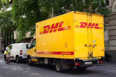 Madrid, İspanya. 1 Haziran 2022. Üzerinde DHL logosu olan sarı bir kargo aracı. Uluslararası bir nakliye ve belge teslimat şirketi. Büyük şehir caddesindeki DHL kamyonu, şehir manzarası. Teslimat aracı