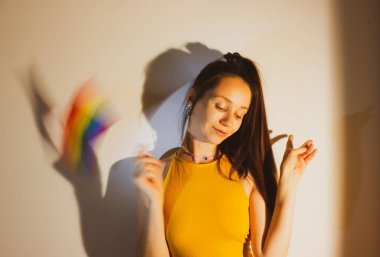 Güzel bir genç kadın, LGBT bayrağını elinde tutan bir kız Onur Ayı 'nı kutluyor. Sevimli seksi kız eğleniyor, gülümsüyor, gülüyor. Gökkuşağı bayrağı - lezbiyenlerin, biseksüellerin, panseksüellerin, eşcinsellerin sembolü. Geliyor..