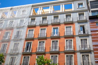 Madrid, İspanya. 2 Haziran 2022 Eski bir binanın restorasyonu. Şehir caddesinde yüksek katlı bir apartmanın cephesi. Duvarda koruyucu cephe şebekesi var. Avrupa 'nın klasik mimarisi.