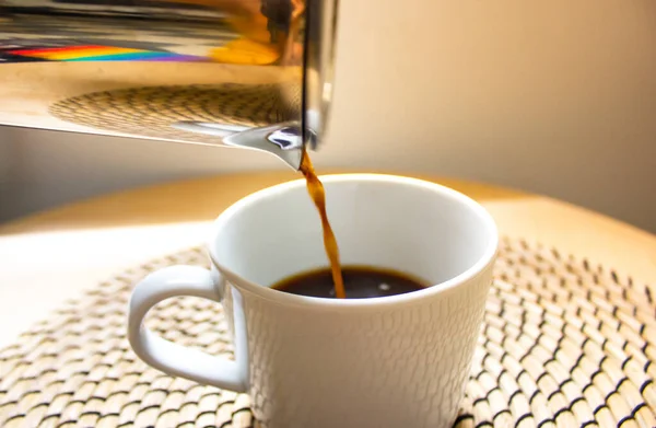 Coffee filter on beige warm background. A process of pouring black coffee into white cup. Morning coffee drink made at home, in a cafe or coffee shop . Geyser coffee maker. Alternative coffee brewing