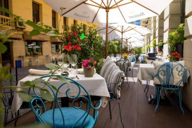 Madrid, İspanya. 9 Mayıs 2022. Boş bir kafe, yemyeşil bir bitki örtüsünün ortasındaki şehir ortamında bir restoran terası. Oturma, konuklara servis edilen eski masa ve sandalyeler. Masa örtüleri üzerinde tablo takımı. 