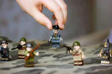 Kyiv, Ukrayna. 9 Mart 2022. Çocuğun elindeki memurun heykeli. Bir çocuk İkinci Dünya Savaşı 'nın LEGO askerlerini oynuyor. Kamuflaj üniformalı oyuncak askerler, makineli tüfek. Silahlı kuvvetlerin savaş askeri oluşumları