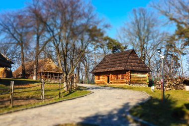 Uzhgorod, Ukrayna. 1 Mart 2021. Geleneksel sazdan çatı evleri olan Ukrayna köyü. Açık havada etno müzesi. Kyiv 'in Kültür Mirası. Baharda bir caddede bir yol bir mesafeye gider..