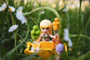 Madrid, İspanya. 1 Mayıs 2022. Oyuncak sarışın LEGO, parktaki yemek alanından dondurma satıyor. Elinde dondurma külahı tutan bir kadın yüksek otların yeşil çimlerinde duruyor yaz tatillerinde beyaz papatyalar..