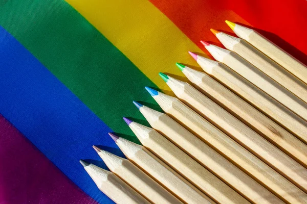 Set of wooden multicolored pencils against a rainbow abstract background. All colors of the rainbow, bright palette. Pride month in June concept. Drawing objects for art school. Education. Back to school