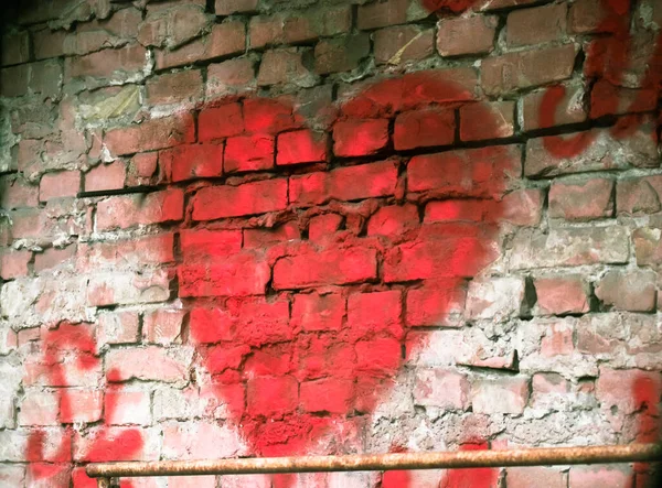 A big red heart painted on a red brick wall. Rough background with a symbol of love. Valentines Day declaration of love on February 14.