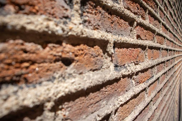 Wall facade of red brick building with contrasting shadows on sunny day SELECTIVE FOCUS. Abstract background of brickwork. Architectural element. Construction, building fragment. Old grunge stones.