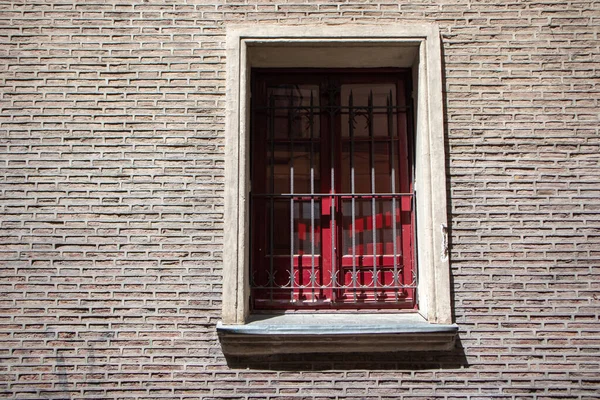 Vintage facade of brick building, red window with metal lattice. European architecture. City street in Madrid, Spain. Details, element of an old buildings. XX century house wall. Exterior in sunny day