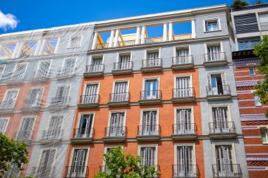 Madrid, İspanya. 2 Haziran 2022 İskeleli eski bir binanın cephesi. Şehir caddesindeki yüksek katlı bir apartmanda restorasyon. Duvarda koruyucu cephe şebekesi var. Avrupa 'nın klasik mimarisi.