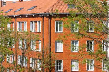 Madrid, İspanya. 7 Haziran 2022. Kırmızı kiremit çatılı, modern kırmızı tuğlalı bir apartmanın ön cephesi. Modern mimari harici detaylar. Bir sürü beyaz plastik pencere. Avrupa evi