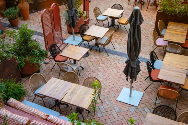 Madrid, İspanya. 1 Haziran 2022. Yazın kafenin, restoranın, butik otelin olduğu teras. Bir sürü boş masa, yukarıdan yeşil bitkiler görünen rahat oturma alanlarında sandalyeler. Bahçe mobilyası