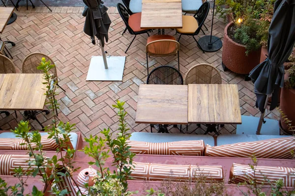 Madrid, İspanya. 1 Haziran 2022. Yazın kafenin, restoranın, butik otelin olduğu teras. Bir sürü boş masa, yukarıdan yeşil bitkiler görünen rahat oturma alanlarında sandalyeler. Bahçe mobilyası