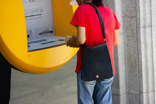 アジアの女性は黄色のAtmから現金を引き出します 金融取引 中国の老婦人は街の通りで屋外でお金を引き出す 銀行のマシンにクレジットカードを挿入する Atmの利用者 — ストック写真