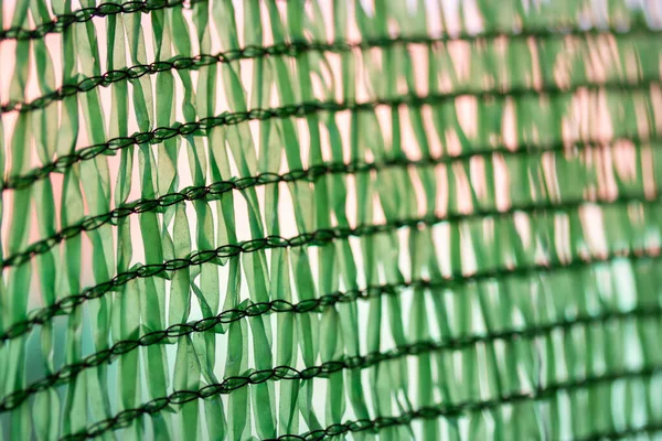 Green protective facade mesh for works on construction site up close. Construction mesh background, texture. Seamless fiber pattern. Construction facade netting to cover scaffolding.