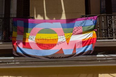Madrid, İspanya. 7 Haziran 2022. Parlak gökkuşağı gay LGBT bayrağı. Şehir caddesinde bir apartmanın balkonunda aşk mesajı var. Gurur Ayı. Uluslararası Homofobi Karşıtı Ulaşım Günü, IDAHOT