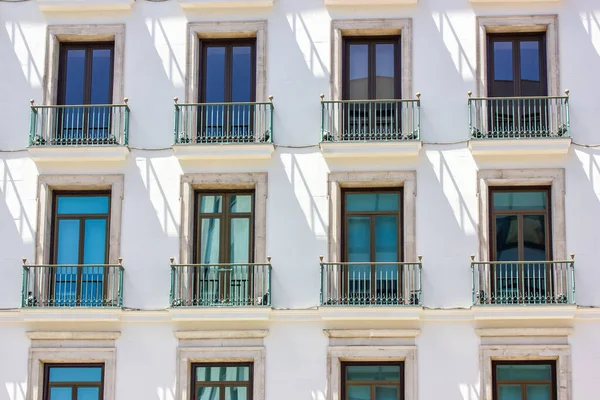 Exterior facade. with many windows, balconies, glass doors. Old house wall. Decorated renovated white building in classic style. Architecture on an urban historic street of Europe. Madrid, Spain.