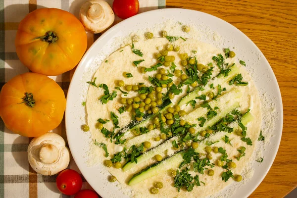 Lavash tortilla wrap with chopped vegetables, cucumbers, tomatoes, cream cheese on a white plate top view. Cooking, healthy food recipe. Food preparing at home in a rustic kitchen wooden table flatly.