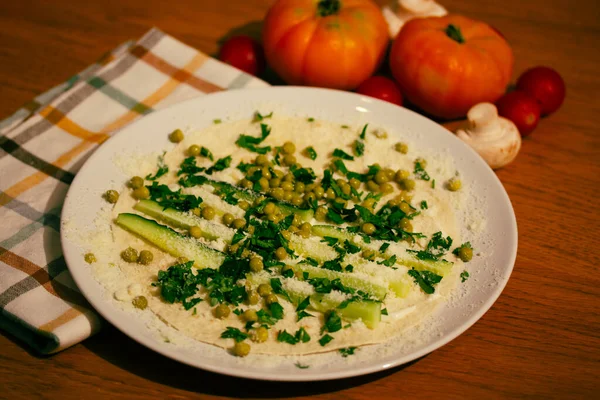 Lavash tortilla wrap with chopped vegetables, cucumbers, tomatoes, cream cheese on a white plate top view. Cooking, healthy food recipe. Food preparing at home in a rustic kitchen wooden table flatly.