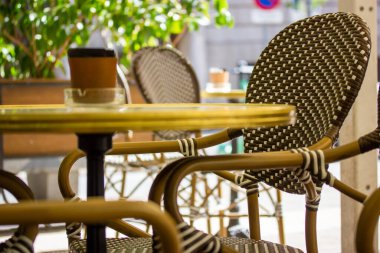 Yaz günü boş eski moda kafe restoranı terası. Sandalyeler ve yuvarlak ahşap masa. Şehir uzayındaki hasır bahçe mobilyaları. Tatillerde dinlenmek için güzel bir yer. Seçici odak.