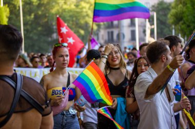Madrid, İspanya. 3 Temmuz 2022 'de farklı gençlerden oluşan bir kalabalık, 2022' de bir gay geçit töreninde şehir caddesinde yürüyor. LGBT sembolleri, gökkuşağı bayrakları kullanıyor. Yaz festivali eğlencesi. Dışarıda rahatla.