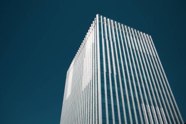 Building exterior. Modern multistory glass facade against blue dramatic sky. Residential house, office buildings, skyscraper. Construction business. Real estate investment. Cityscape view. Urban scene