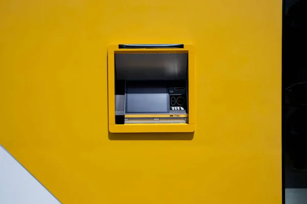Automated teller machine (ATM). Cash dispenser on yellow wall. Account balances, withdraw, deposit money, transactions in bank concept. Finance, credit, payments theme. A point of issue of banknotes.