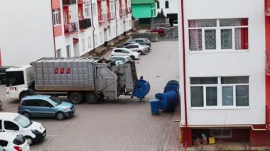 Uzhgorod, Ukraine. May 1, 2022. Garbage trucks, junk collection workers load waste from the containers into a garbage truck. The residential courtyard of apartment buildings. City urban infrastructure