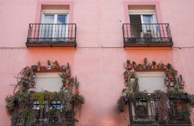 Madrid, İspanya. 2 Haziran 2022. Mercan pembesi bir evin ön cephesi. Çiçeklerle süslenmiş otantik balkonlar, doğal ışıkta kaktüsler. Avrupa 'nın geleneksel mimarisi. Seyahat yönü