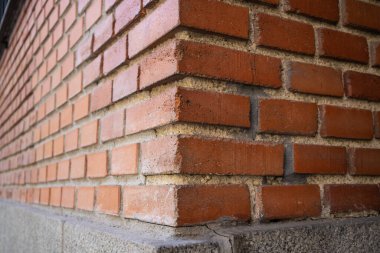 Corner of a red brick building, home in perspective. The concept of building houses, residential real estate. Architectural details. The exterior of the building. Orange brick and concrete.