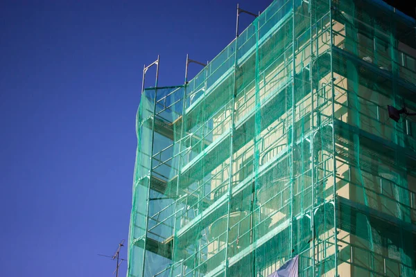 Multistory Building Facade Covered Green Protective Construction Mesh Blue Sky — Stok fotoğraf