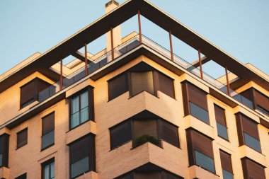 Madrid, Spain. May 1, 2022. Corner of a modern residential high-rise brown brick monolithic building, house against blue sky. Architecture in the style of postmodernism, brutalism Details of architect