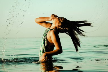 Teenage girl 10-13 years old frolicking playing in blue water. A child dives in and out of a water. Little girl has fun in sea ocean on summer vacation. Schoolgirl with wet hair in swimsuit having fun