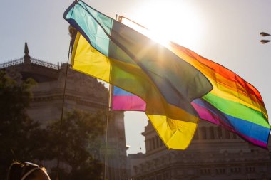 Ukrainian flag and rainbow LGBT flag against a sunny sunset sky. A symbol of nationality and freedom, sexual orientation. Support gay community on rally, Pride month concept. Nation democracy symbol. 