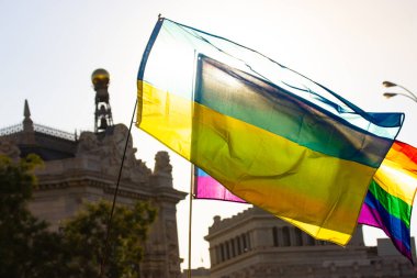 Ukrainian flag and rainbow LGBT flag against a sunny sunset sky. A symbol of nationality and freedom, sexual orientation. Support gay community on rally, Pride month concept. Nation democracy symbol. 