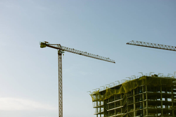 Construction of a residential high-rise multistory modern house building in a metropolis city. Construction crane on horizon. Buildings under construction against sky. Housing business. New flats home