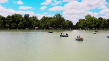 Madrid, İspanya. Mayıs 12022 Göl göleti mavi suyla, birçok turistli tekne yüzüyor. Eğlence parkında eğlence yeşil ağaçlı Retiro Parkı, güneşli yaz gününde uçan bulutlar hızlandırılmış video