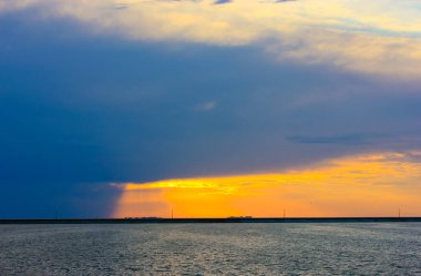Denizde bir fırtına. Akşamları mavi denizin üzerinde asılı duran mavi bir yağmur bulutu. Turuncu-mavi gökyüzü. Bir okyanus, bir nehir, bir su kütlesi. Ufukta dalgalar var. Sakin fırtınalı ufuk çizgisi.