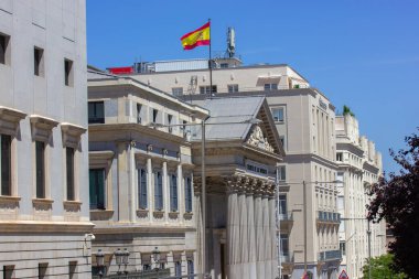 Madrid, İspanya. 1 Ağustos 2022 İspanya başkentinin tarihi merkezi. Avrupa şehrinin hükümet binasında eski bir mimari. İspanyol bayrağı olan bir evin çatısının ön cephesi. 