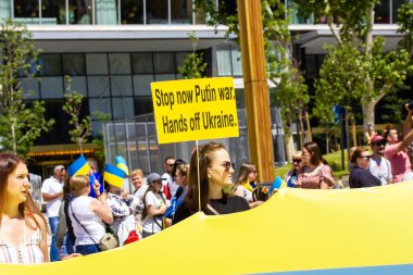 Madrid, İspanya. 1 Ağustos 2022 Ukrayna 'daki savaşı protesto eden bir grup insan. Sarı pankartlı bir kadın. Savaşa son verin, Ukrayna 'dan uzak durun. Bir toplantıda vatanseverler, ralli. Ukrayna bayrakları.