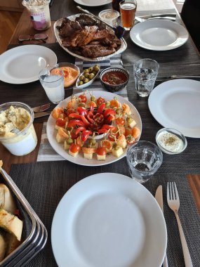 Köy ahşap masada ızgara et ve sebzelerle servis edilen peynir tabağı.